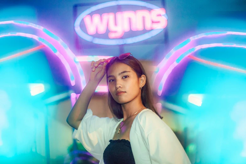 a female wearing a black and white shirt a neon sign and some lights