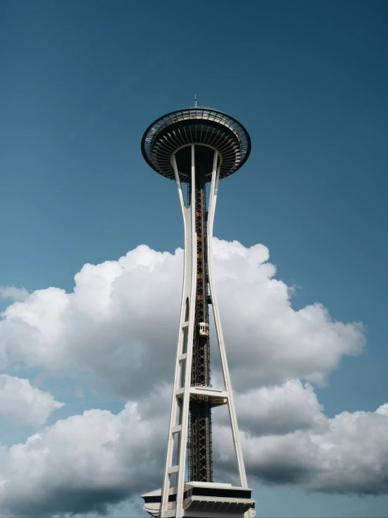 a tall white tower with a lot of clouds