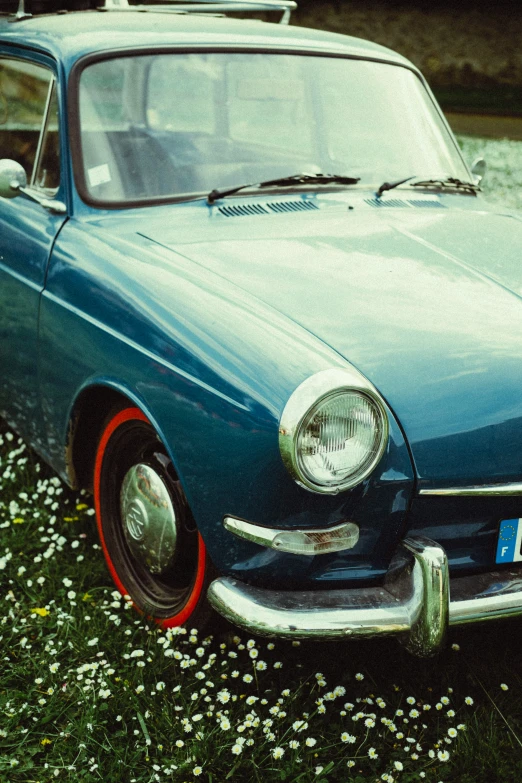 an old car parked on top of grass with daisies around it
