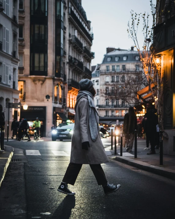 person walking down an open city street at dusk