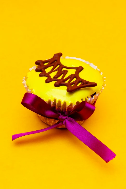 a cupcake decorated with a purple ribbon and a pink bow