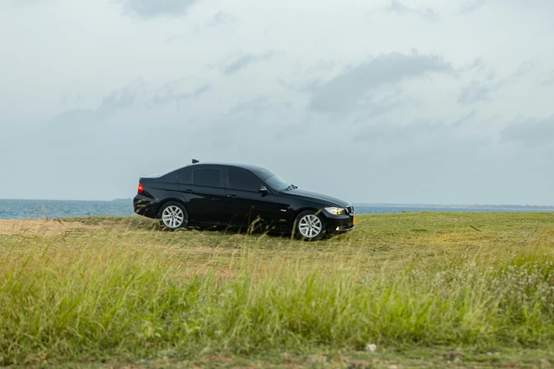 a black car sits on a grassy field