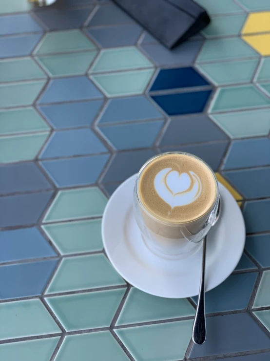 coffee with the letter e in it sits on top of a saucer