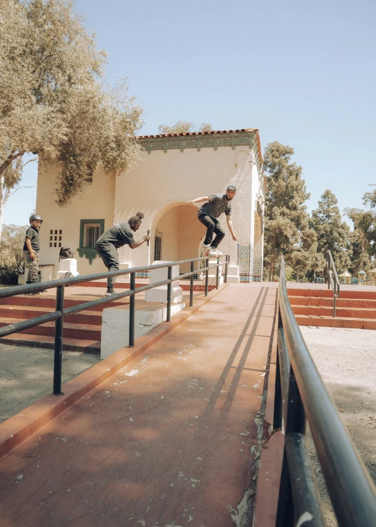 three people doing tricks on their skateboards off the side of a rail