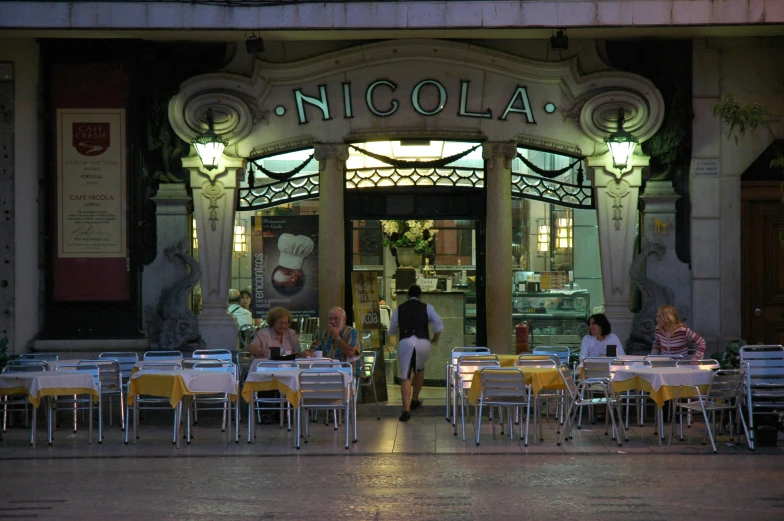 people sitting at tables outside of an upscale cafe