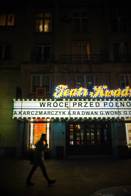 the neon sign for a theatre on an urban street