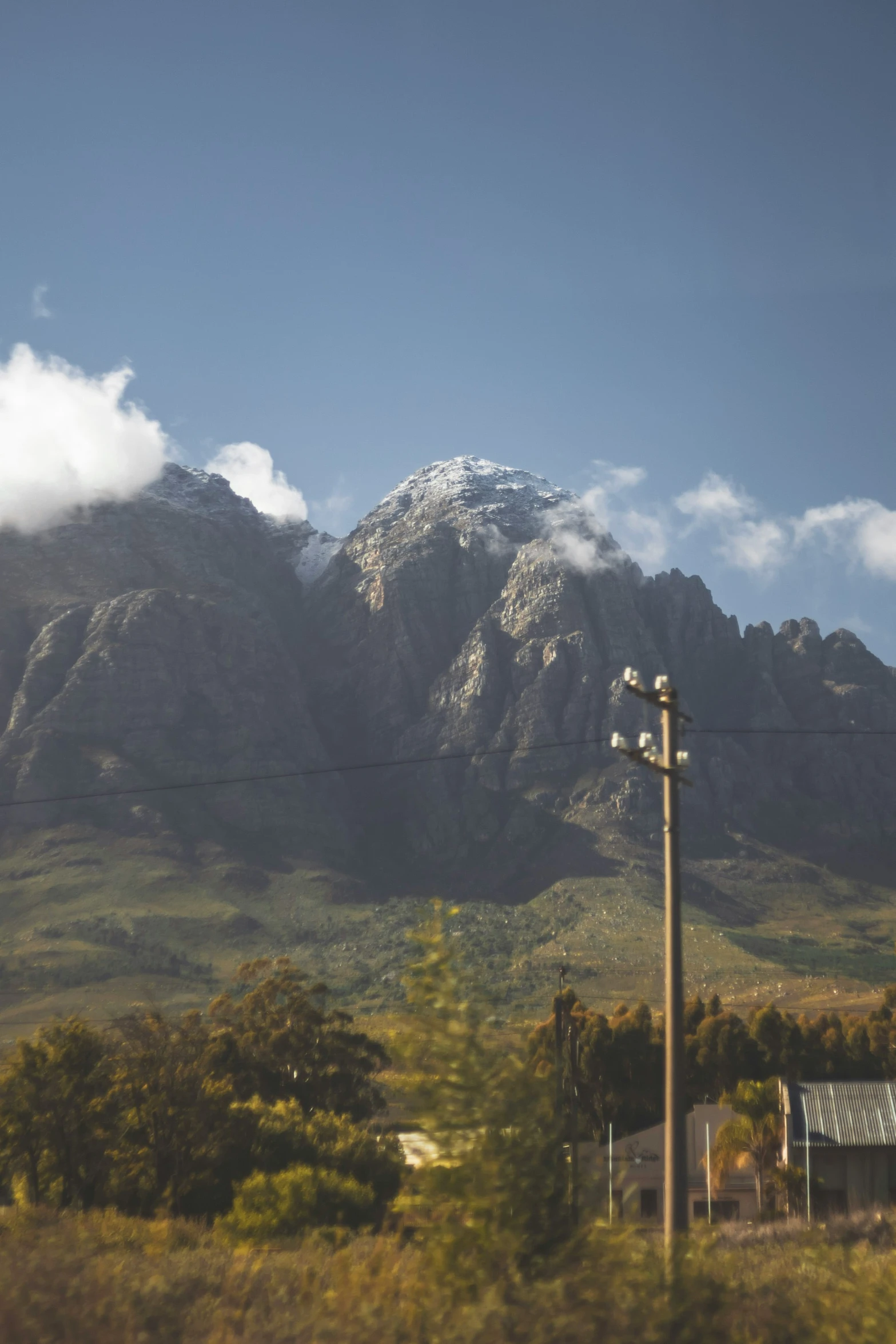 a view of some mountains, a traffic light and a house in the distance