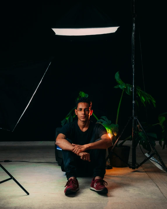 a young man kneeling down in front of his po shoot setup