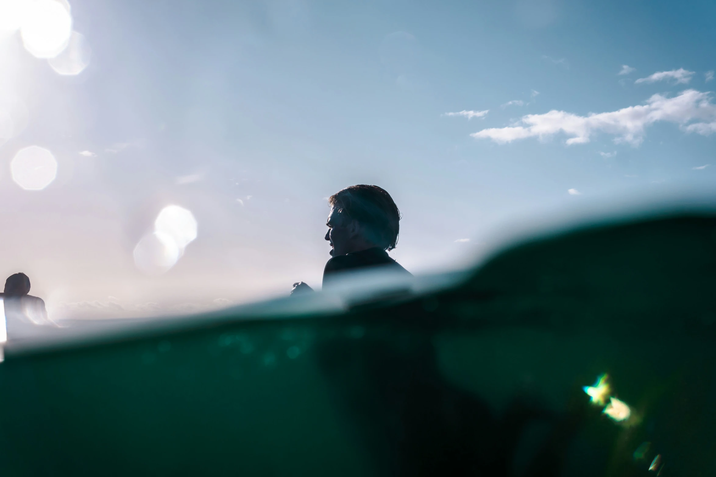 someone standing out of the water looking at a person with sun shining