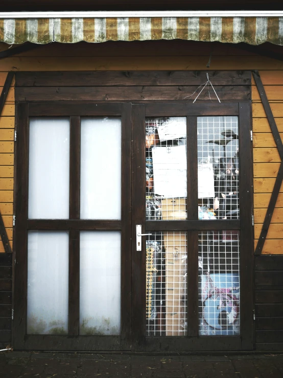 the wooden door of an old - fashioned building has many windows and wire bars