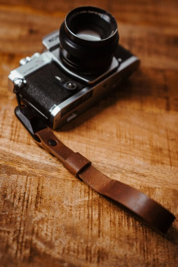 a camera is sitting on the table with a leather strap around it