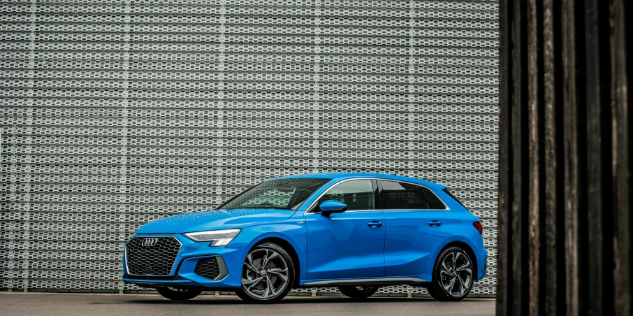 a blue audi car parked in front of a wall