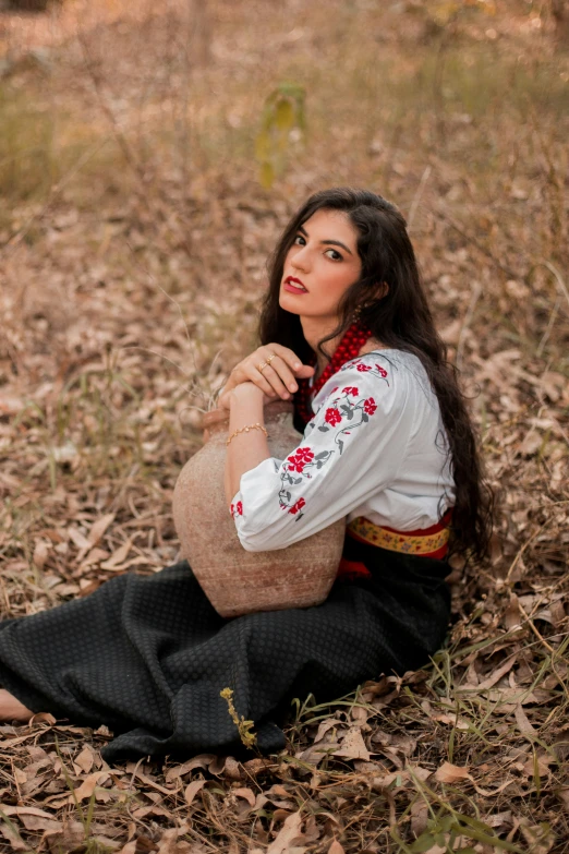 a woman sitting on top of a leaf covered ground