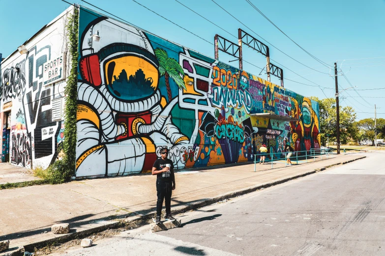 man standing in front of an enormous painted building