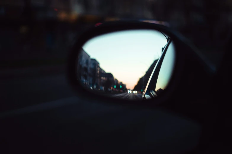 a rear view mirror reflecting the back of a building
