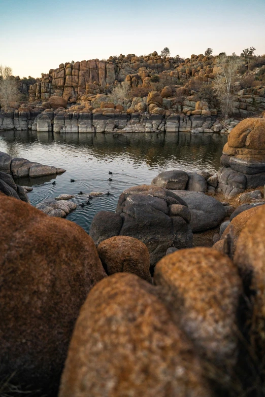 many rocks by the water near some mountains