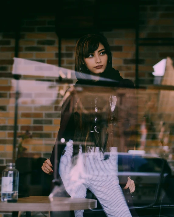 a woman leaning on a glass door by a brick building