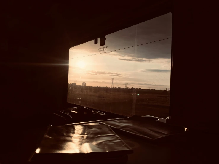 sun behind a horizon over the landscape from a train window