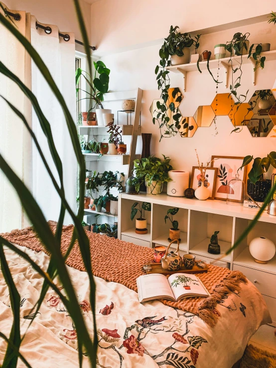 a bed with blankets, pillows and plants on the headboard