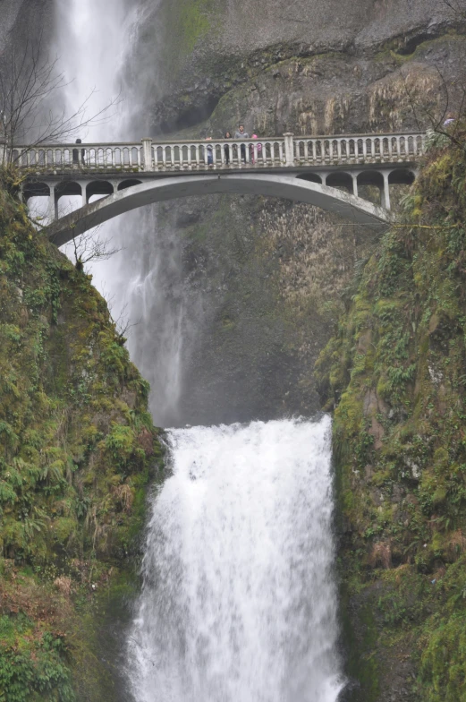 a bridge over a body of water that has a waterfall under it