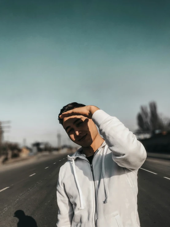 a man in a hoodie standing on a highway