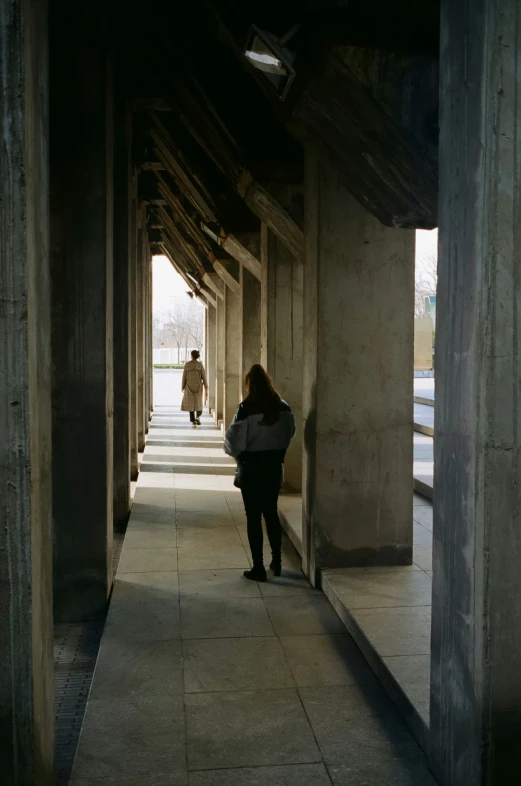 a woman walks down a walkway past many columns