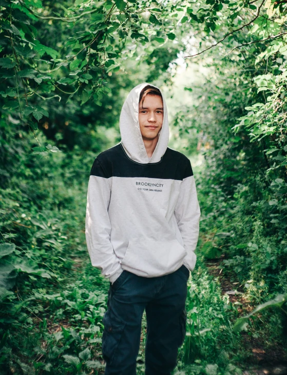 young man posing for a po while standing in the middle of a forest