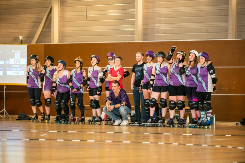 a group of rollerbladers watching some young women skating on a ramp