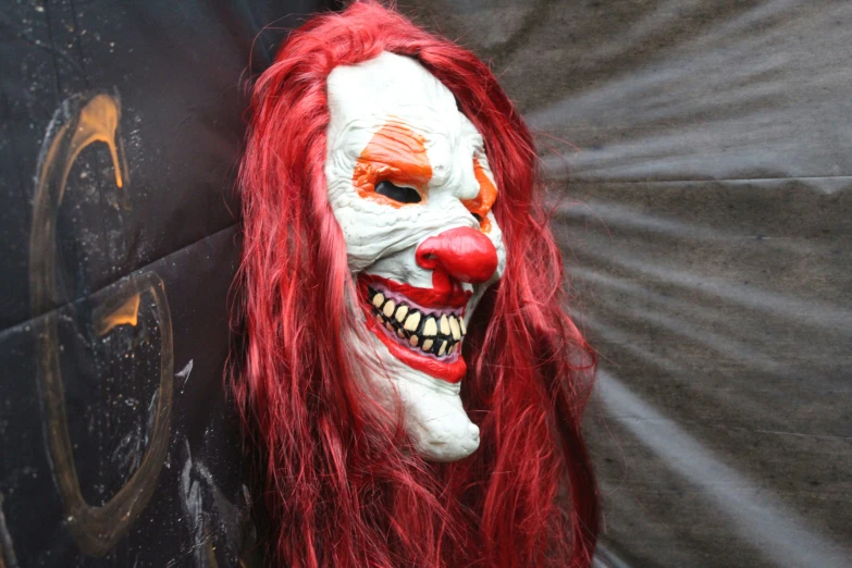 a close up of an scary clown mask with red hair