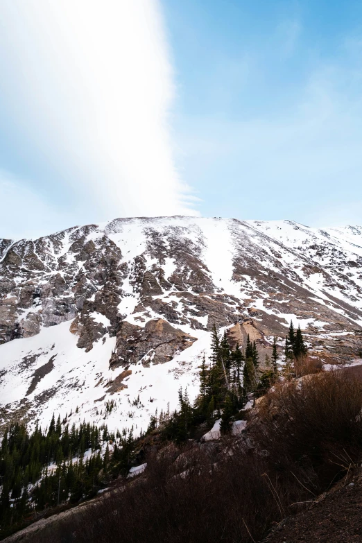 a man with a helmet and backpack standing on a snow covered mountain top