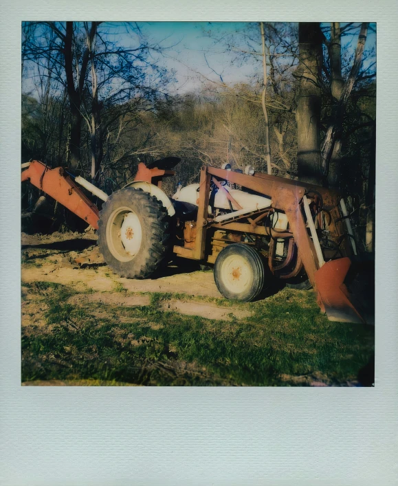 the tractor is parked in the field near some trees