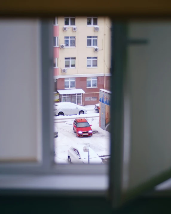 a red car parked in a parking lot in front of a building