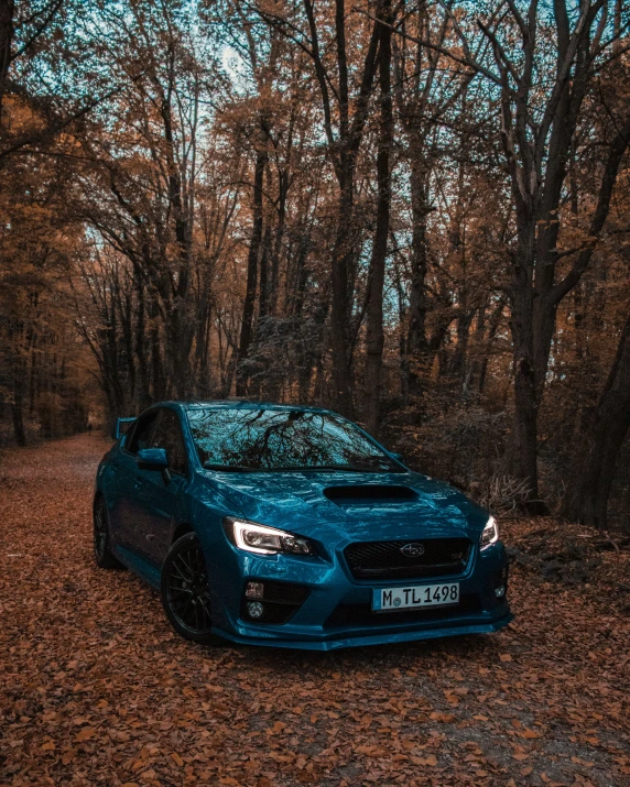 there is a blue sports car parked in the middle of a trail