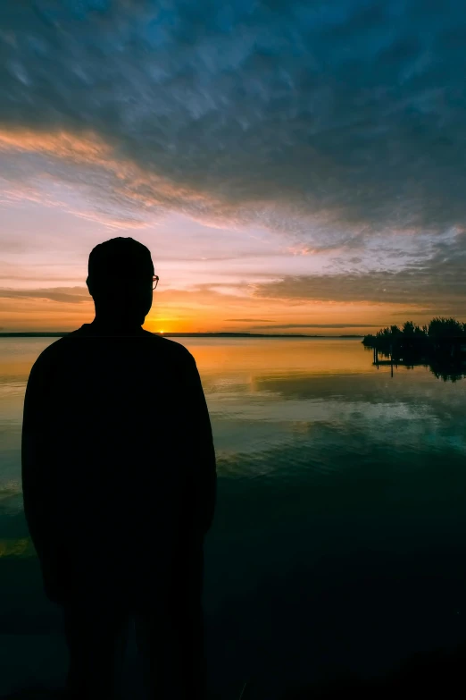 a silhouette of a man on the edge of a body of water