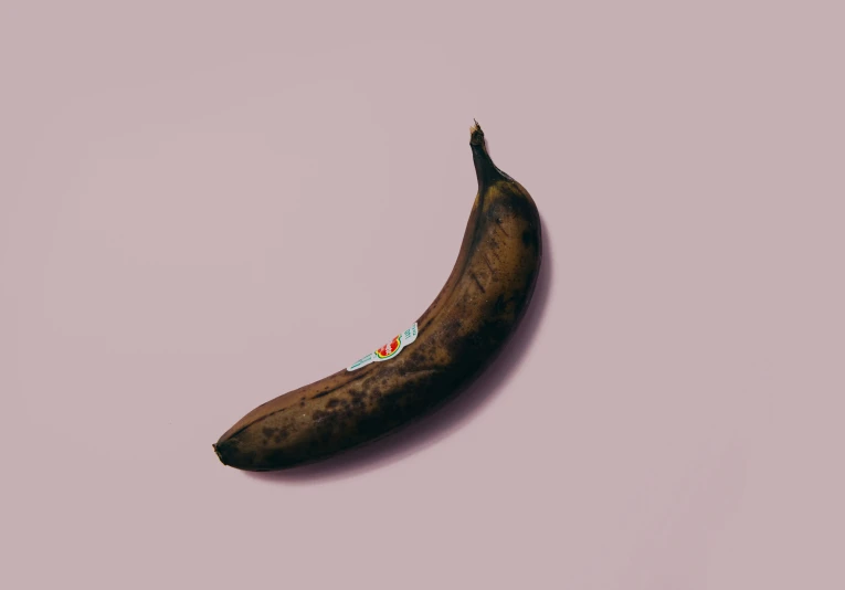 a ripe banana laying on a pink surface