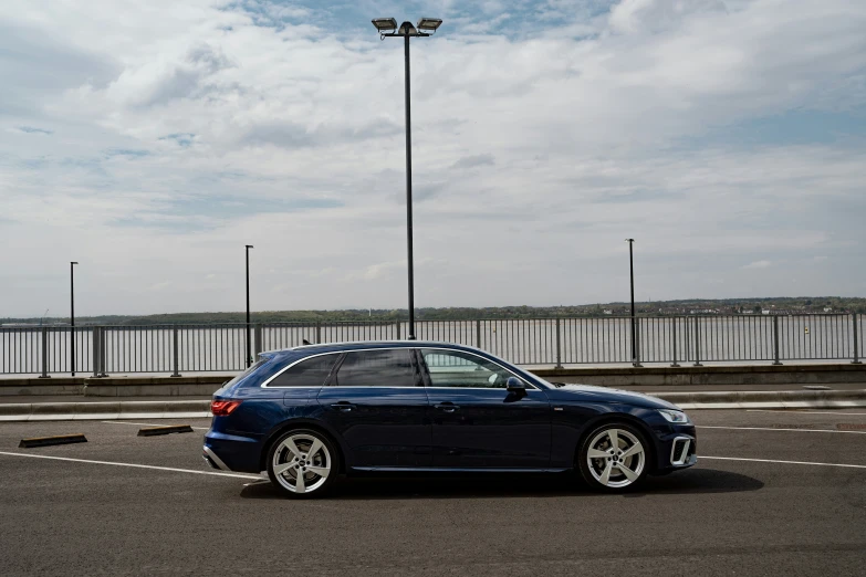 a blue car sits in a parking space next to a fence and street lights