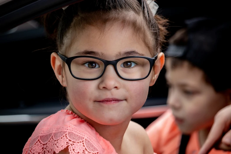 a girl wearing glasses sitting in the passenger seat of a car