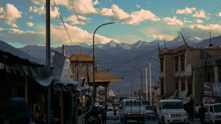 a street with buildings, cars and people walking in the middle