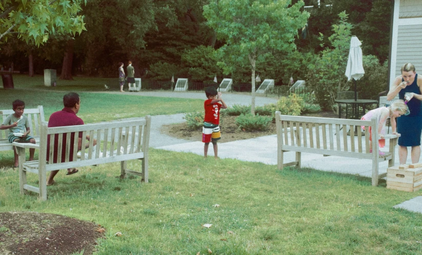 a small child is sitting on a bench near two adults and one child