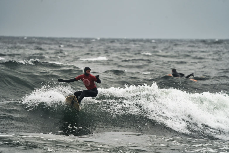 a man surfing on the water in front of another surfer