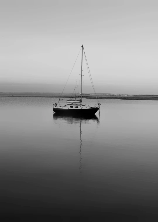 a sailboat is seen in a foggy bay