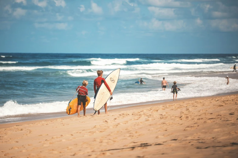 two people with surfboards walking on the beach