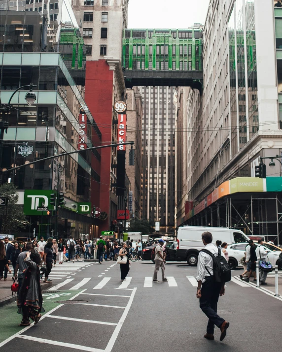 people are crossing the street with cars, and skyscrs