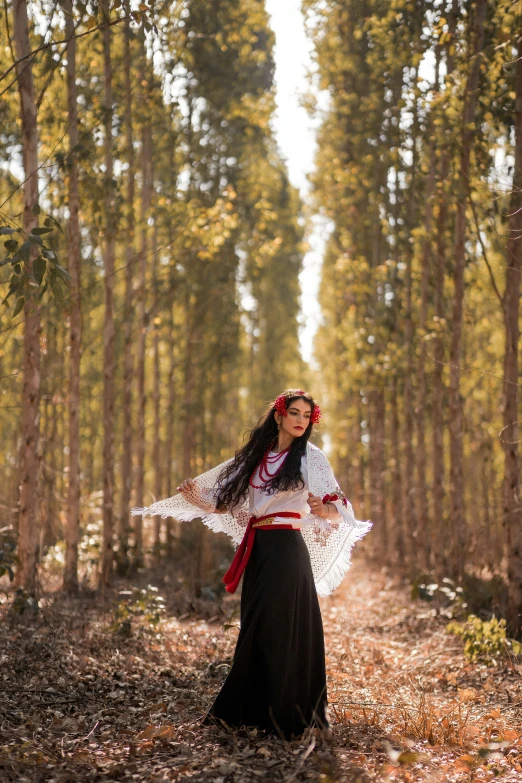 a woman with a frock is walking through a wooded area