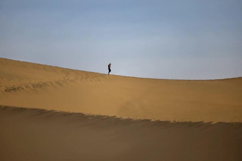 a man is walking across a very tall dune