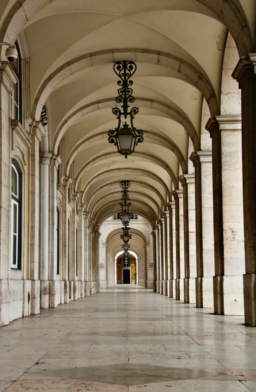 the long and empty hallway has pillars, lantern lights and arches