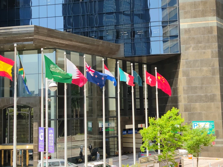 several flags are flying outside of an office building