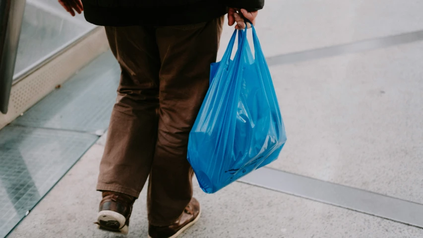 there is someone walking down the sidewalk carrying bags