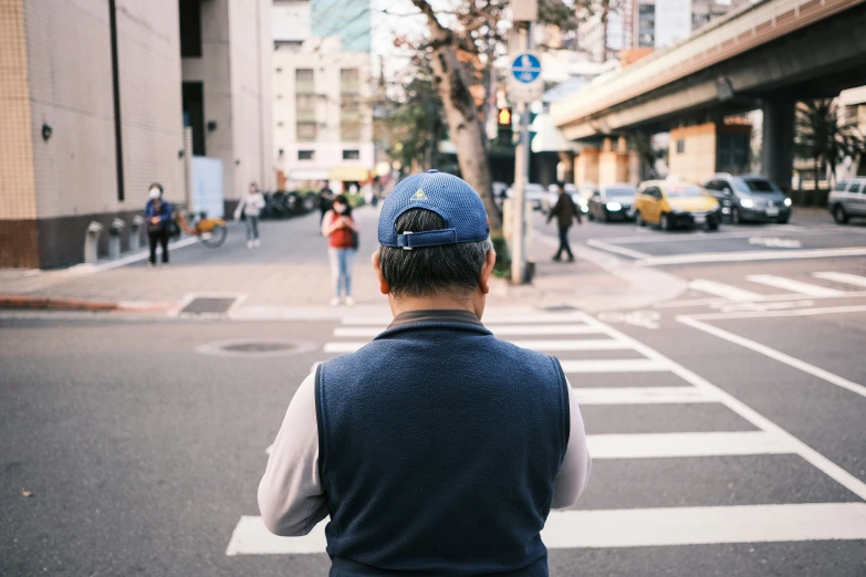 man wearing a blue cap is stopped at an intersection