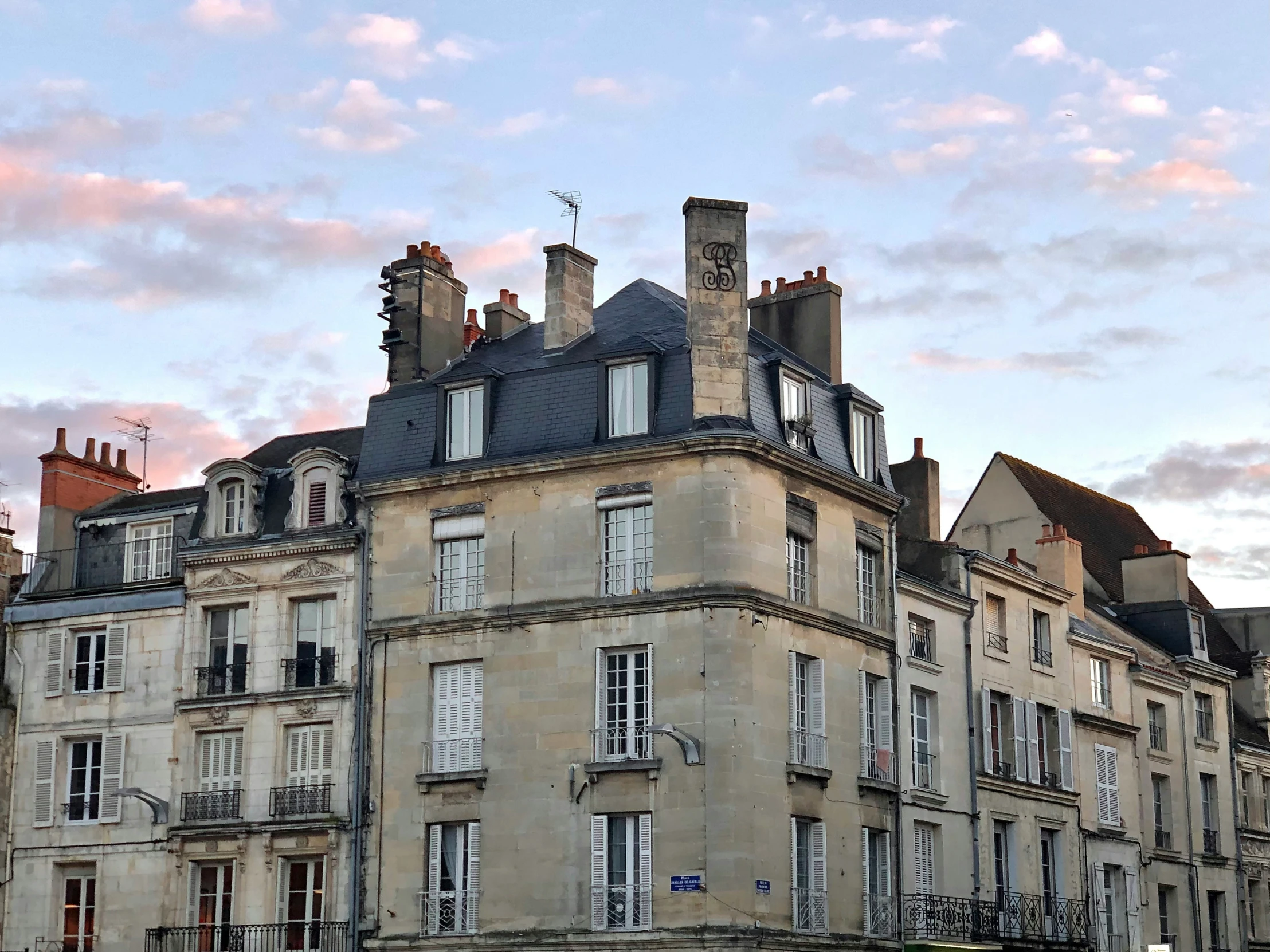 an old building sits under a colorful cloud filled sky